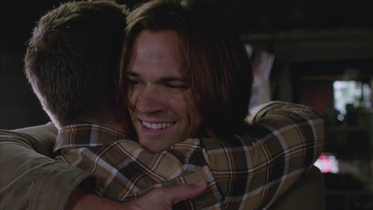 A cheery Sam hugging Dean